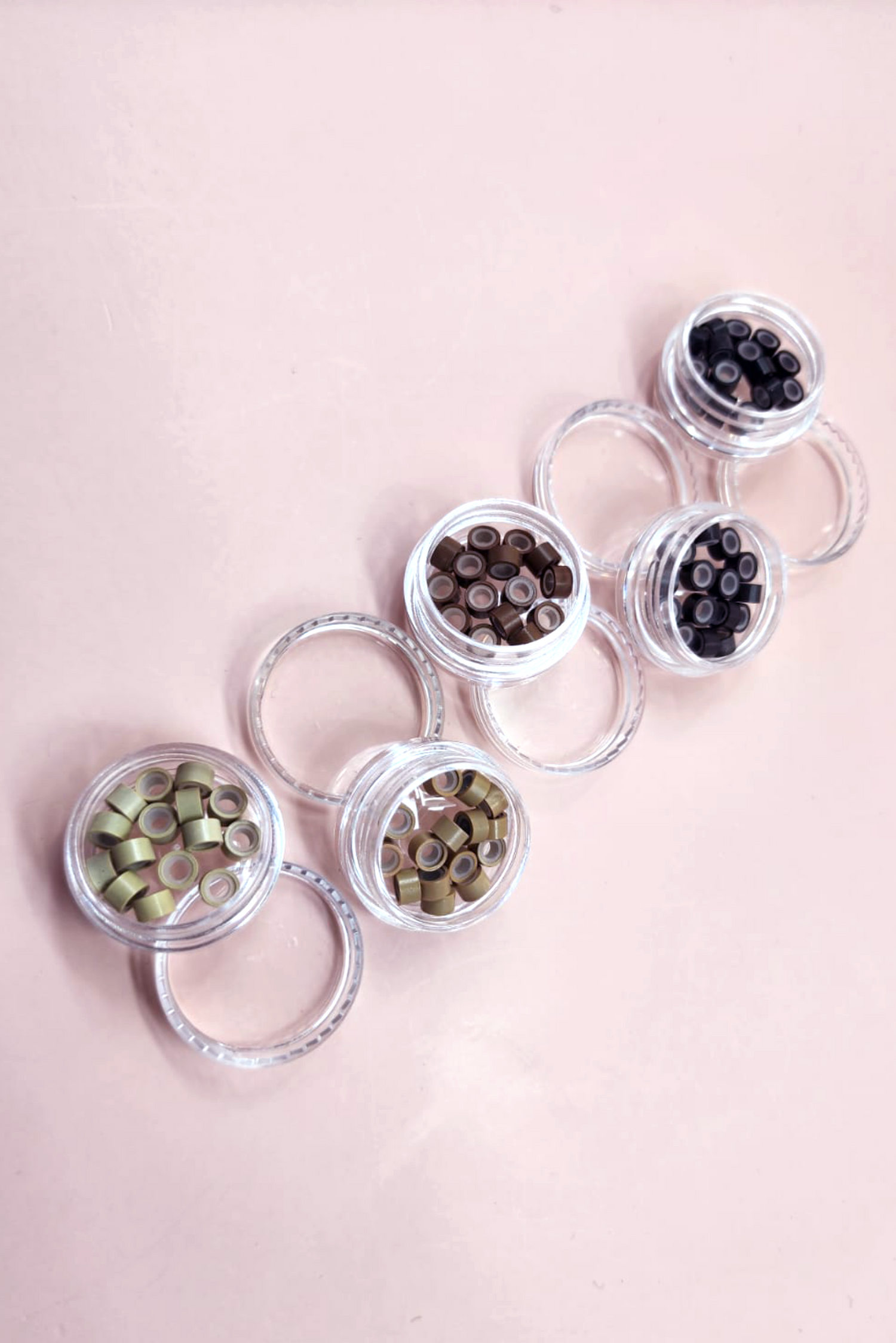 מיכלים שקופים שבתוכם חרוזי מעיכה לתוספות שיער בצבעי שחור, חום כהה, חום בהיר, שטני ובלונדיני