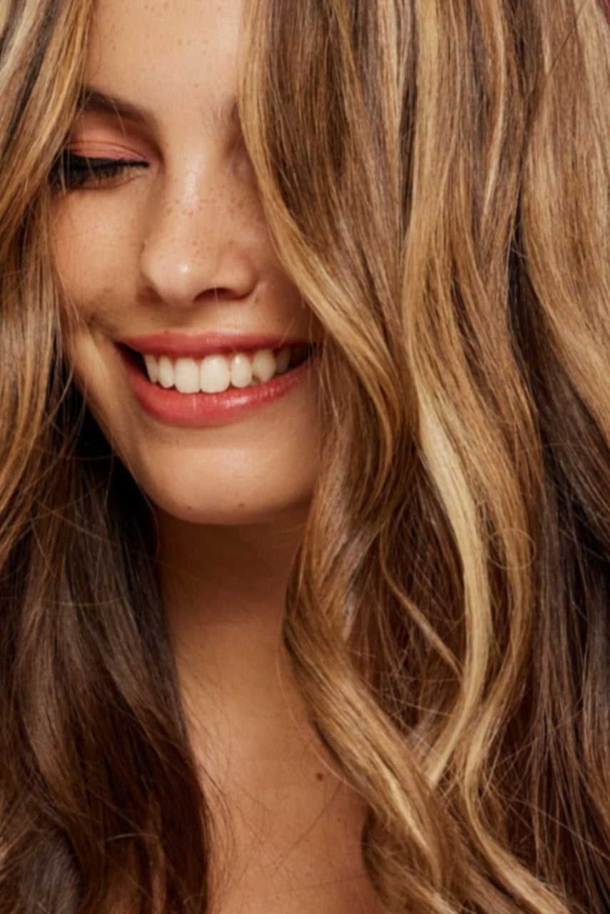 קלוז אפ של בחורה שבשיער שלה שזורים גווני שיער טבעיים, גליים - בצבע בלונד זהוב - תוספות השיער מיועדות לחיבור עצמאי, פשוט  וקבוע לשיער או לחיבור זמני - Shufizoo לשיער