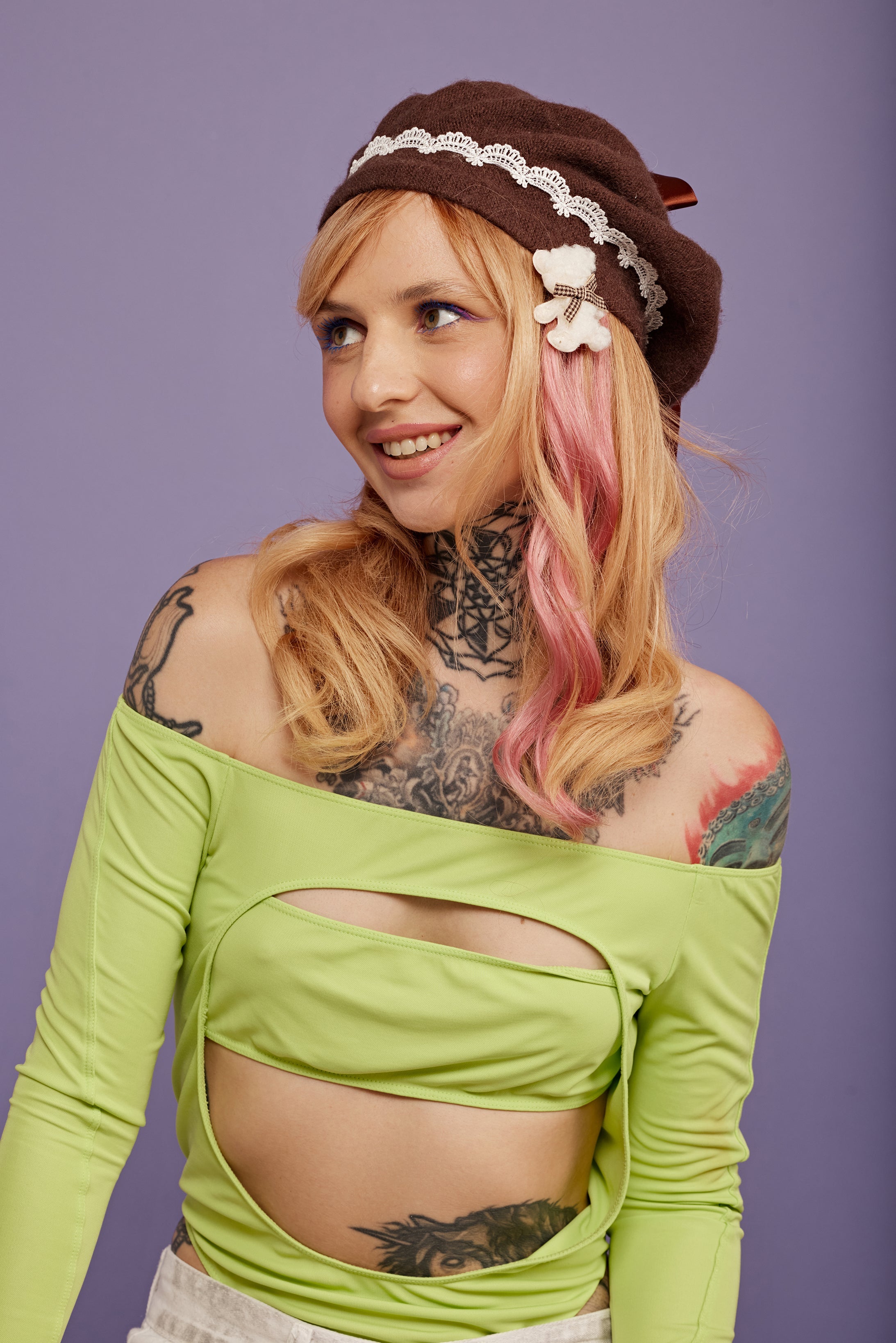 מדיום שוט של בחורה, חובשת כובע ברט חום, מעוטר תחרה לבנה. היא עונדת סיכת דובי לבנה. על השיער יש לה תוספות שיער בצבע ורוד עתיק - Shufizoo