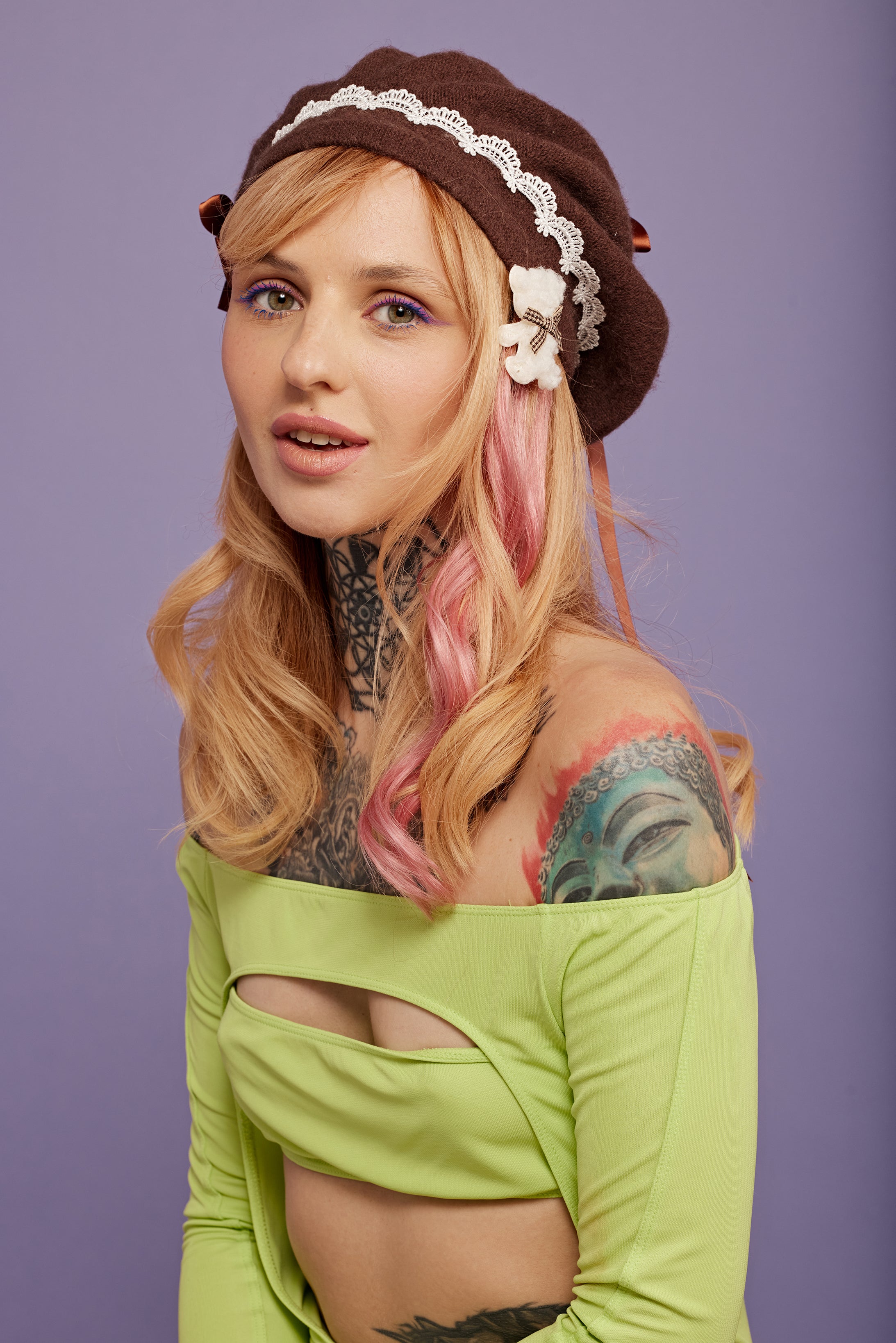 מדיום שוט של בחורה, חובשת כובע ברט חום, מעוטר תחרה לבנה. היא עונדת סיכת דובי לבנה. על השיער יש לה תוספות שיער בצבע ורוד עתיק - Shufizoo