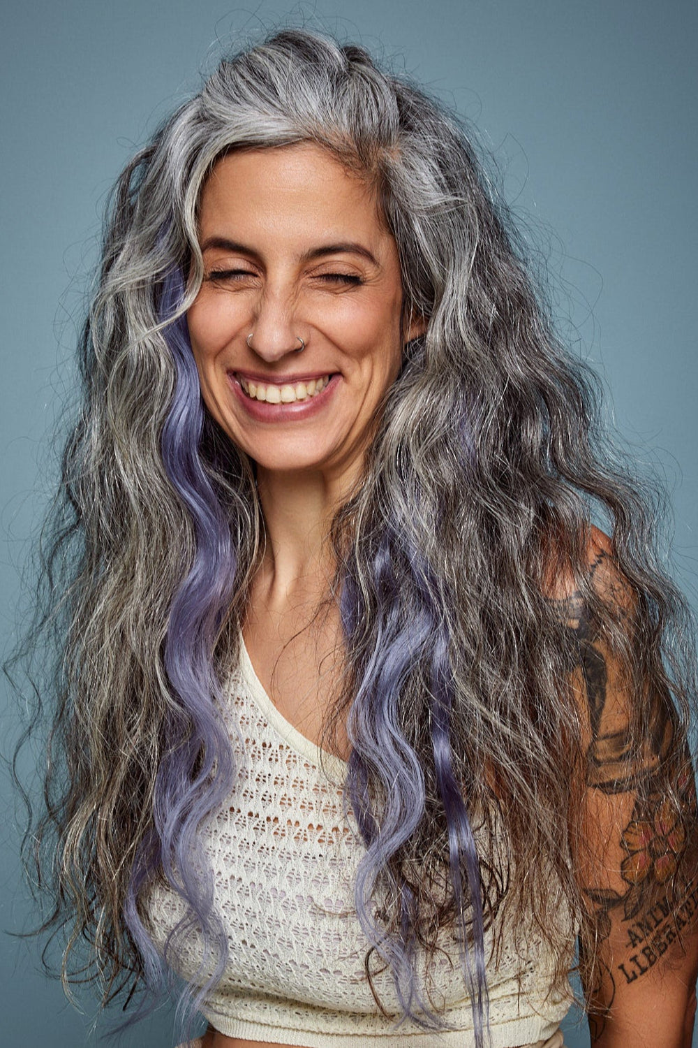 מדיום שוט של בחורה שבשיער שלה שזורים גווני שיער טבעיים, גליים - בצבע כחול אפור כהה  - תוספות השיער מיועדות לחיבור עצמאי, פשוט  וקבוע לשיער או לחיבור זמני לשיער  - Shufizoo 