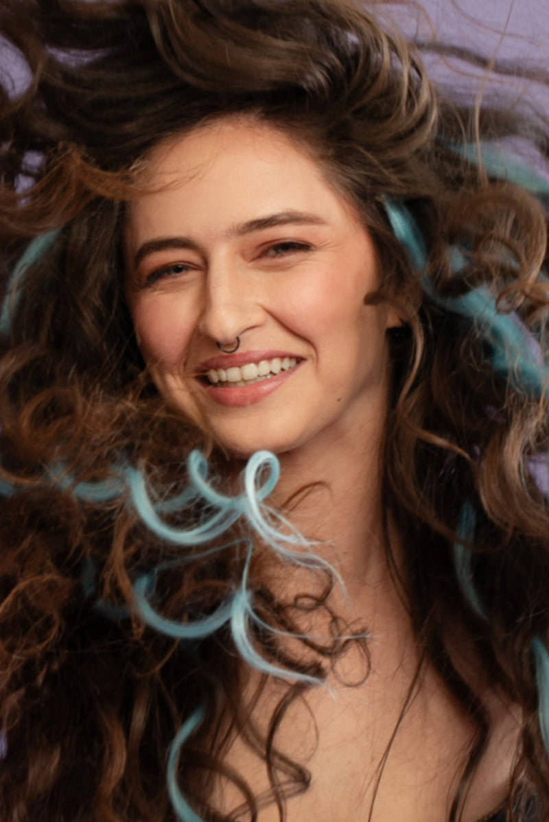 קלוז אפ של בחורה שבשיער שלה שזורים גווני שיער טבעיים, גליים - בצבע תכלת - תוספות השיער מיועדות לחיבור עצמאי, פשוט  וקבוע לשיער או לחיבור זמני לשיער  - Shufizoo 