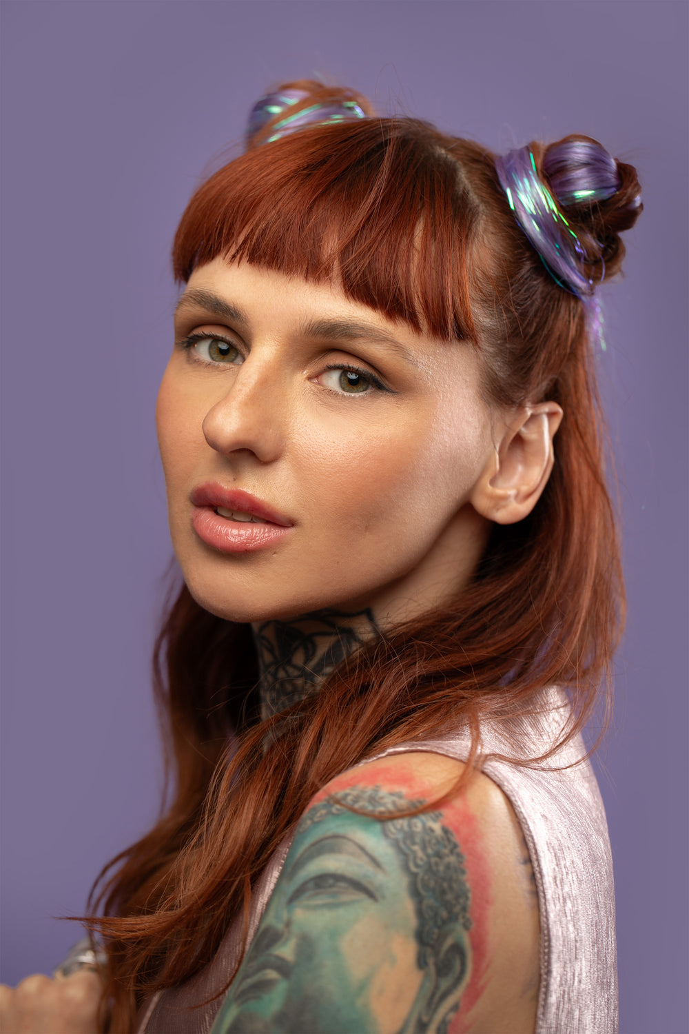 קלוז אפ של בחורה עם 2 גולגולים, שבשיער שלה שזורים גווני שיער טבעיים, חלקים - בצבע סגול לילך - תוספות השיער מעורבבות עם גווני פיות זוהרים ומיועדות לחיבור עצמאי, פשוט  וקבוע לשיער או לחיבור זמני לשיער  - Shufizoo 