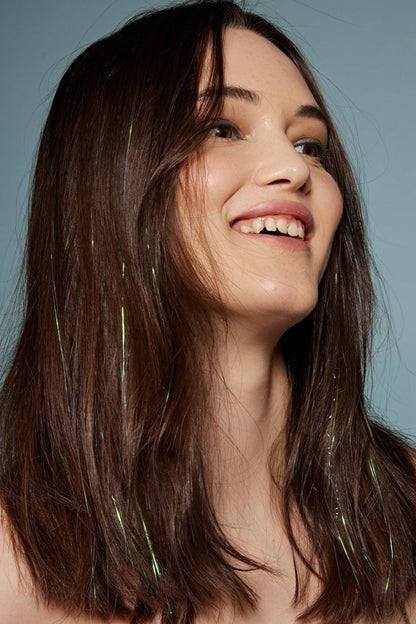 קלוז אפ של בחורה שבשיער שלה שזורים חוטי טינסל בצבעי לבן זוהר - הנקראים אצלנו גווני פיות. מיועדים לחיבור עצמאי, פשוט וקבוע לשיער או לחיבור זמני - Shufizoo