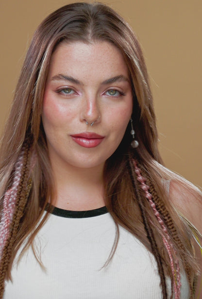 סרטון של בחורה, המהדקת רצועת עור בצבע חום אל השיער שלה. אל רצועת העור מחוברות צמות, ראסטות ותוספות שיער.