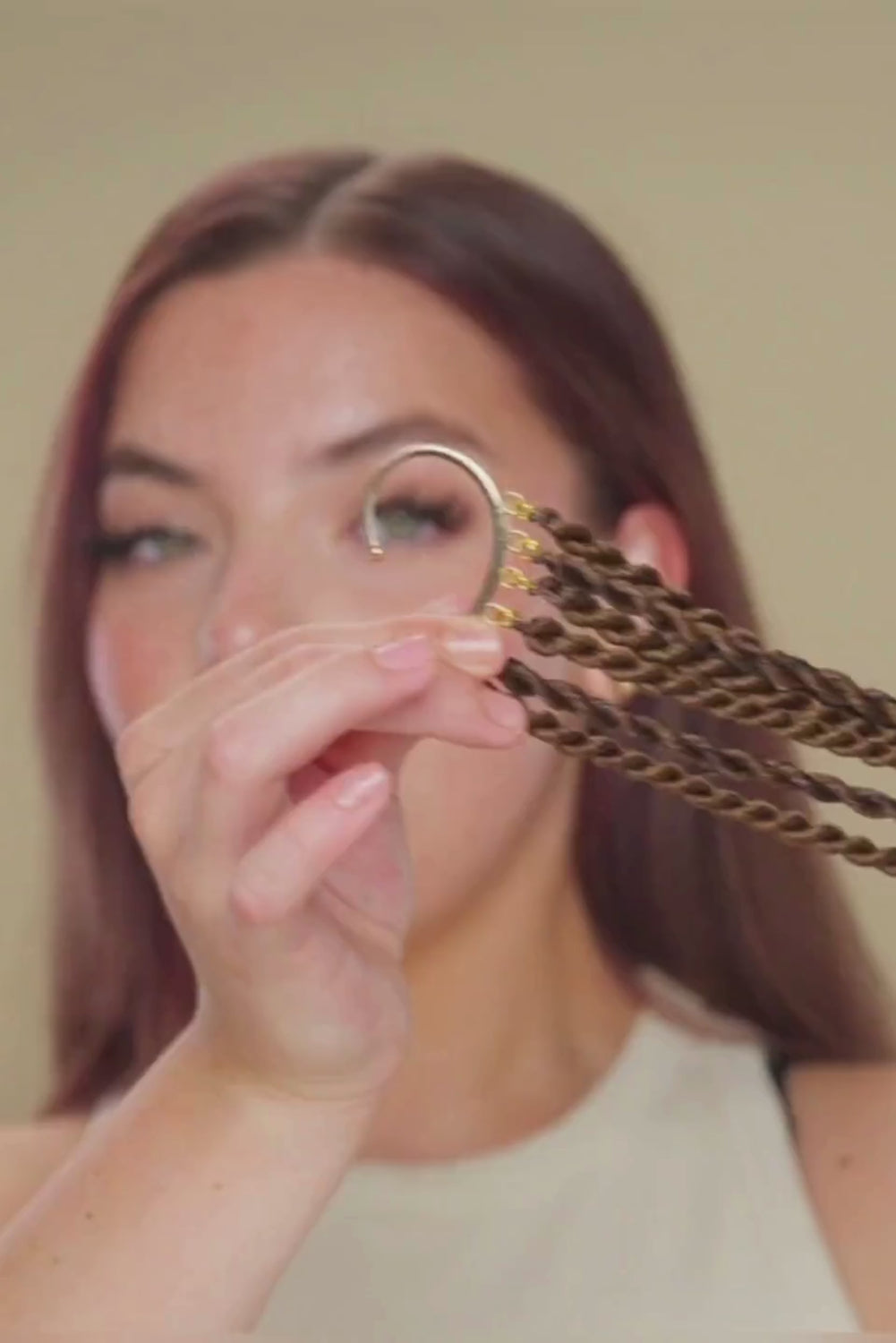 סרטון של בחורה, המחיקה תכשיט בצורת חצי עיגול, שאליו מחוברות צמות חבל. את התכשיט היא מלבישה על אחורי האוזן